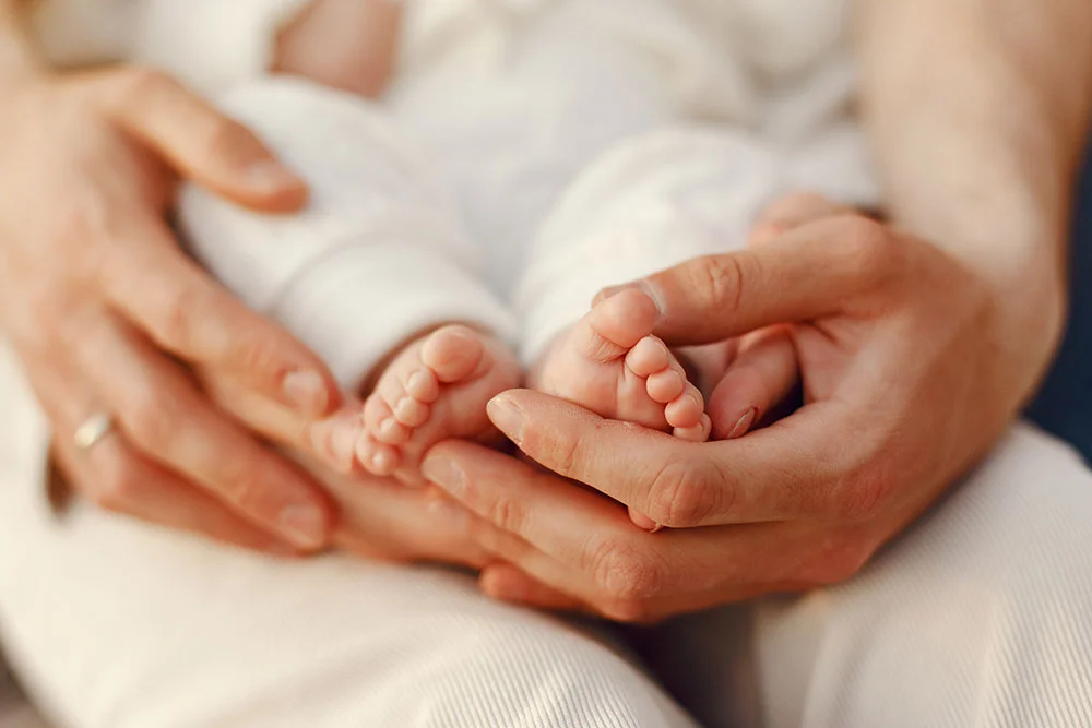 Mãos de pais segurando os pezinhos de um recém-nascido
